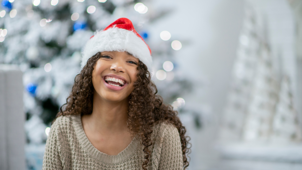 Woman with a Santa head smiling. Image to blog post: The 12 Days of Dental Tips for a Healthy Holiday Smile