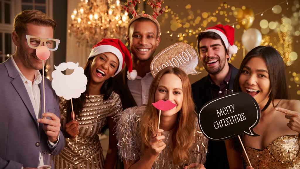 Group of friends holding photo props at a holiday party. Image for blog post for Andrew Wheatley, DDS in Norman, OK : Image for Teeth Whitening Tips for the Holidays: Jingle All the Way to a White Smile 