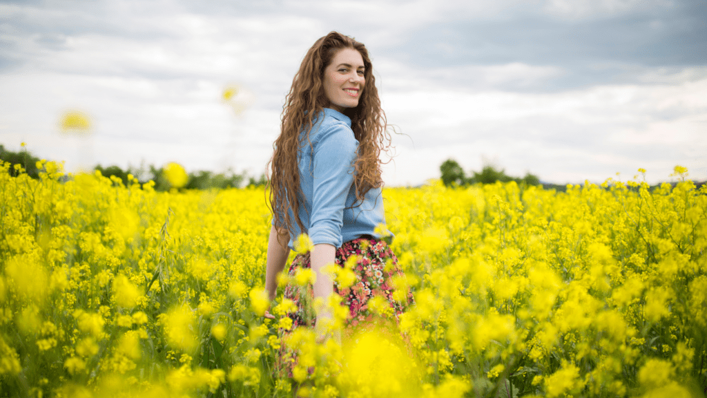 Woman standing in a field of flowers. Spring Cleaning for Your Smile
